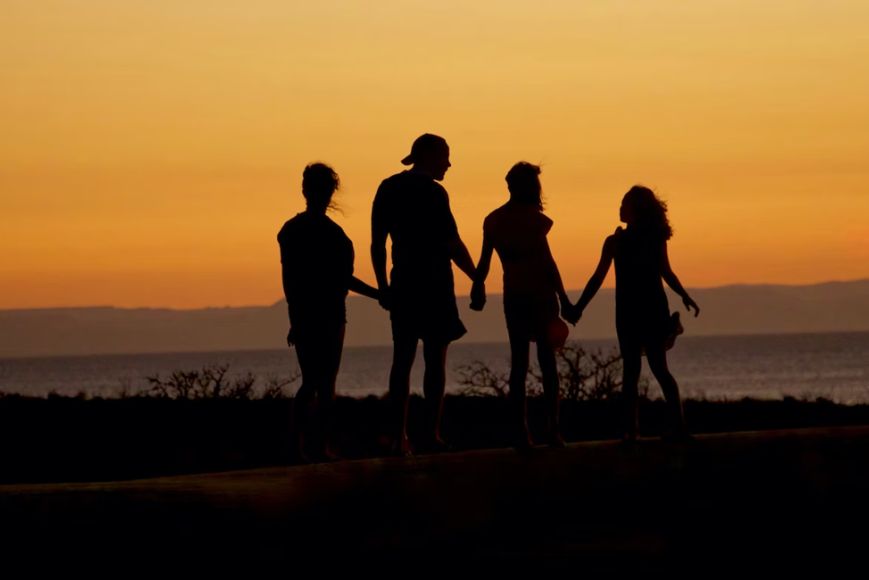 family holding hands in sunset at the beach