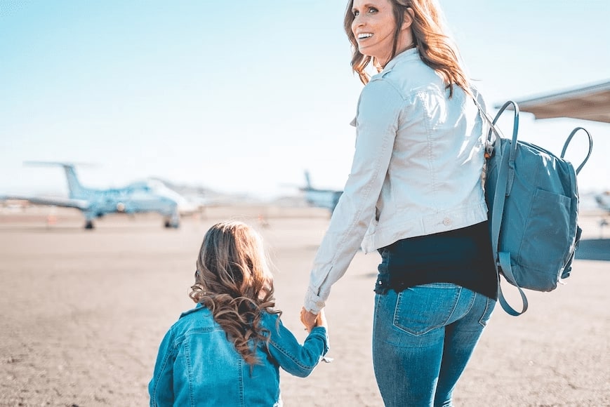 mom with backpack and child walking towards airplane